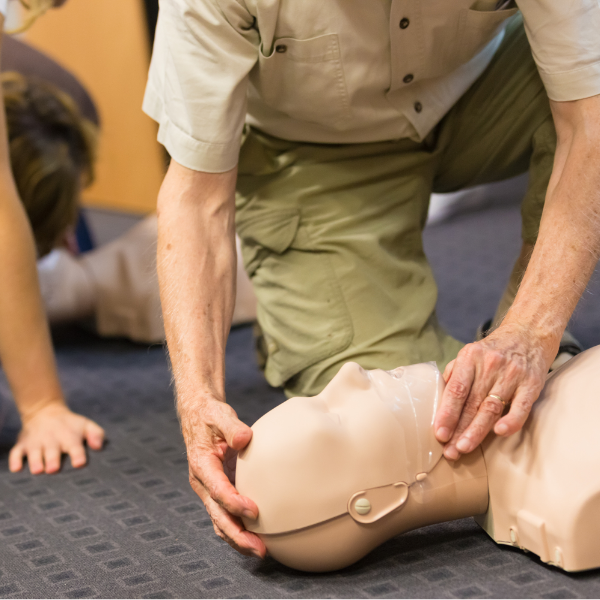 A man is performing cpr on an infant dummy.