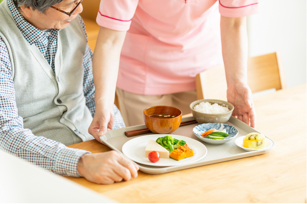 A woman serving food to an elderly person.