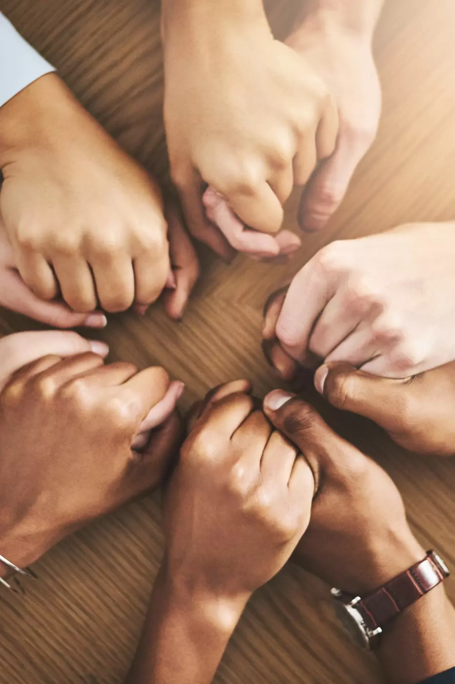 A group of people holding hands on top of a wooden floor.